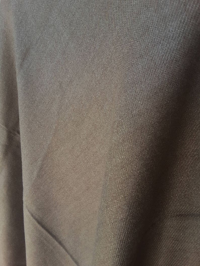 Puede incluir: Primer plano de una tela gris oscuro con un tejido texturizado sutil. La tela tiene una superficie lisa y uniforme y un acabado ligeramente brillante.