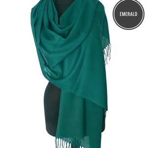 Può includere: Una morbida sciarpa di pashmina di colore verde smeraldo con bordi a frangia. La sciarpa è drappeggiata su un manichino.