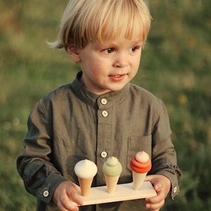 Toddler holding a wooden ice cream toy set with three pastel cones — Montessori pretend play food.