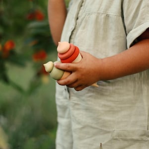 Child playing with wooden ice cream pretend play toy outdoors — neutral Montessori style toy.