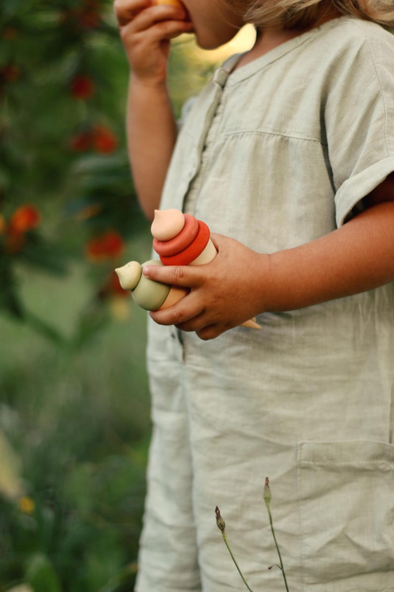 Child playing with wooden ice cream pretend play toy outdoors — neutral Montessori style toy.