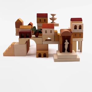 May include: A wooden toy set featuring a miniature village with houses, a fountain, and a statue. The set is made of natural wood and painted in warm, earthy tones.