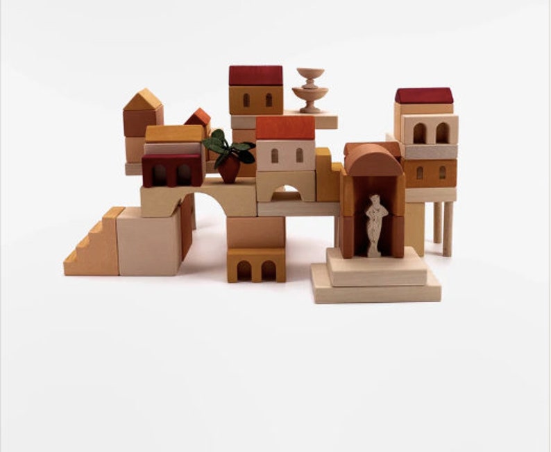 May include: A wooden toy set featuring a miniature village with houses, a fountain, and a statue. The set is made of natural wood and painted in warm, earthy tones.