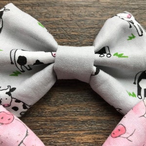 May include: A gray bow tie with a white and black cow print. The bow tie is made of fabric and has a simple design.