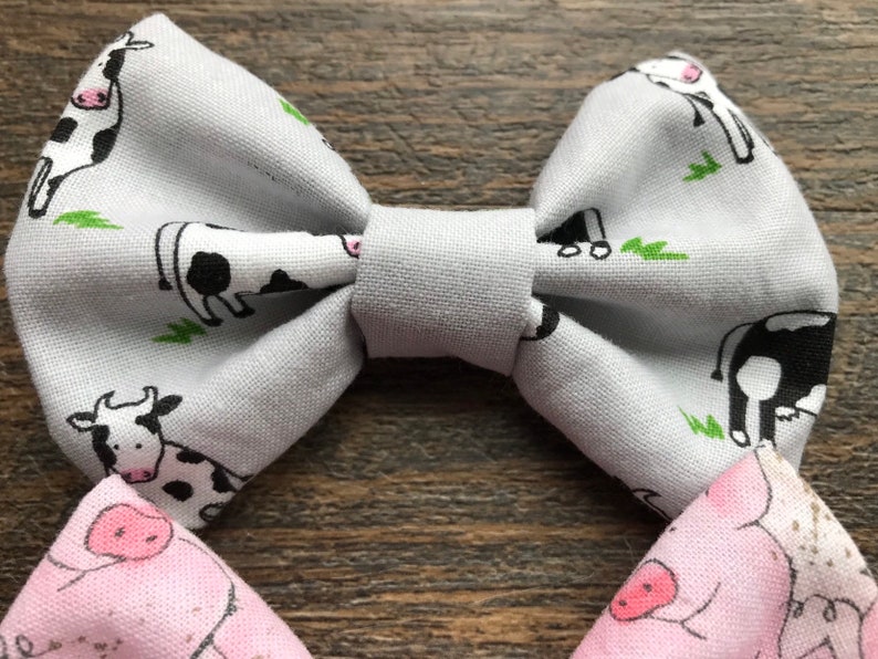 May include: A gray bow tie with a white and black cow print. The bow tie is made of fabric and has a simple design.