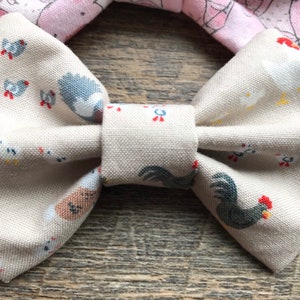 May include: A beige bow tie with a white and gray chicken print. The bow tie is made of fabric and has a simple design.