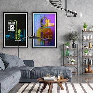 May include: Two framed posters on a gray wall. The poster on the left is black with a green saxophone and the text "SOMETHING ELSE". The poster on the right is purple with a keyboard and the text "Head Hunters".