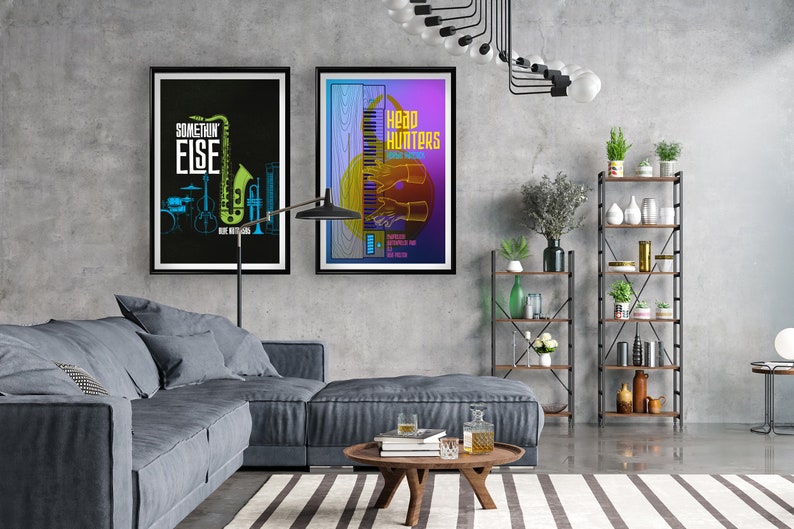 May include: Two framed posters on a gray wall. The poster on the left is black with a green saxophone and the text "SOMETHING ELSE". The poster on the right is purple with a keyboard and the text "Head Hunters".