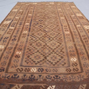 K&ouml;nnte beinhalten: Ein brauner und beigefarbener Teppich mit geometrischem Muster. Der Teppich hat ein traditionelles Aussehen und ist aus Wolle gefertigt.