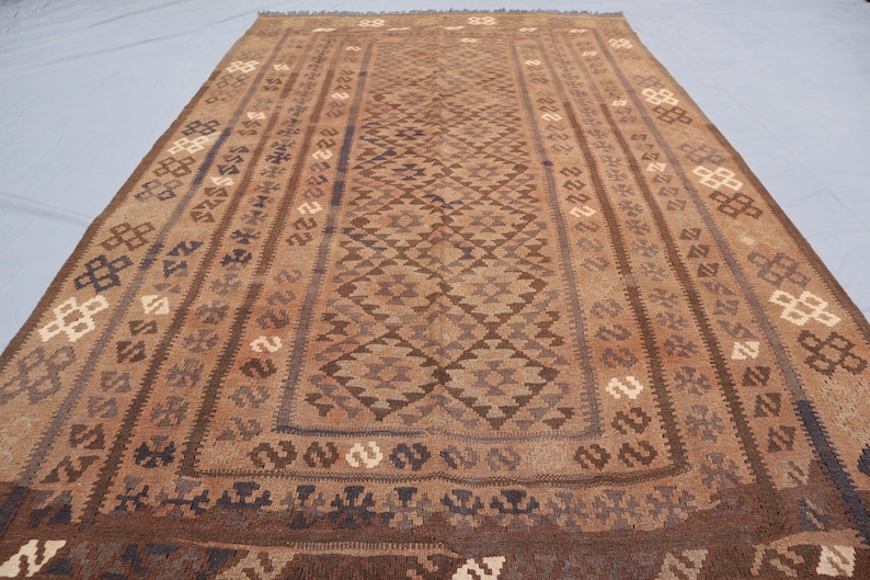 K&ouml;nnte beinhalten: Ein brauner und beigefarbener Teppich mit geometrischem Muster. Der Teppich hat ein traditionelles Aussehen und ist aus Wolle gefertigt.