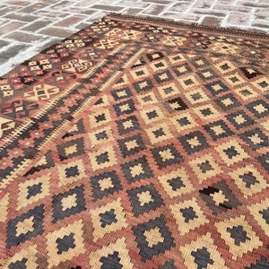 K&ouml;nnte beinhalten: Ein Vintage-Teppich mit einem geometrischen Muster in Braun-, Beige- und Rott&ouml;nen. Der Teppich hat einen abgenutzten und verblassten Look, der ihm ein rustikales und antikes Aussehen verleiht.