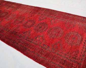 May include: A red runner rug with a black and white geometric pattern. The rug has a fringe on the ends.