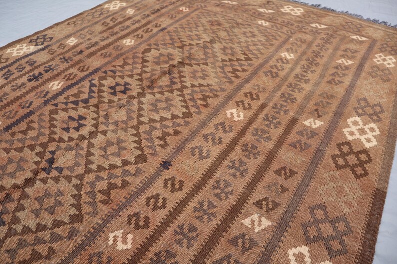 K&ouml;nnte beinhalten: Ein brauner und beigefarbener Teppich mit geometrischem Muster. Der Teppich hat ein traditionelles Aussehen und ist aus Wolle.