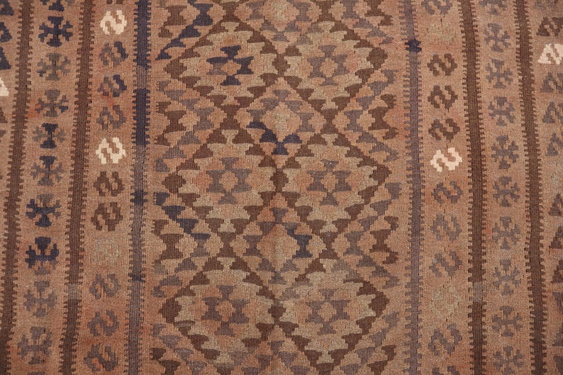 K&ouml;nnte beinhalten: Ein brauner und beiger Teppich mit geometrischem Muster. Der Teppich hat ein Rautenmuster mit einem kleineren Rautenmuster in jeder Raute. Der Teppich ist aus Wolle und hat eine weiche Textur.