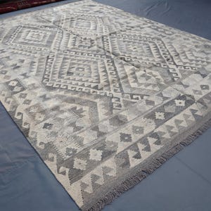 May include: A gray and white patterned rug with a diamond design. The rug has a fringe border.