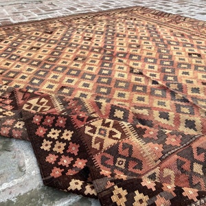 K&ouml;nnte beinhalten: Ein antiker t&uuml;rkischer Teppich mit einem geometrischen Muster in Braun-, Beige- und Rott&ouml;nen. Der Teppich ist in der Mitte gefaltet, wodurch die komplizierten Details des gewebten Designs sichtbar werden.