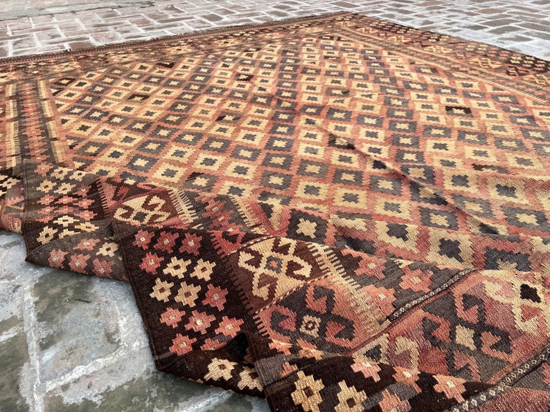 K&ouml;nnte beinhalten: Ein antiker t&uuml;rkischer Teppich mit einem geometrischen Muster in Braun-, Beige- und Rott&ouml;nen. Der Teppich ist in der Mitte gefaltet, wodurch die komplizierten Details des gewebten Designs sichtbar werden.