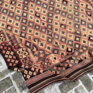 K&ouml;nnte beinhalten: Ein antiker t&uuml;rkischer Teppich mit einem geometrischen Muster in Rot-, Braun- und Beiget&ouml;nen. Der Teppich ist gefaltet und hat einen Fransenrand.