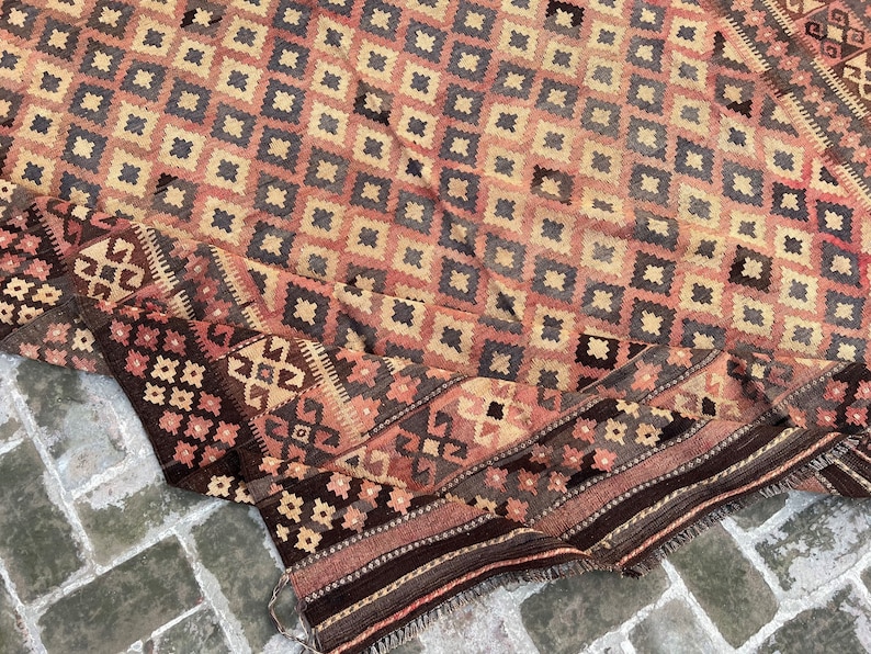 K&ouml;nnte beinhalten: Ein antiker t&uuml;rkischer Teppich mit einem geometrischen Muster in Rot-, Braun- und Beiget&ouml;nen. Der Teppich ist gefaltet und hat einen Fransenrand.