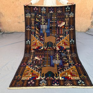 May include: A rectangular, dark blue rug with a detailed, symmetrical design. The rug features brown animal figures, geometric patterns, and colourful accents in red, yellow, and blue. The rug has a cream-coloured fringe.
