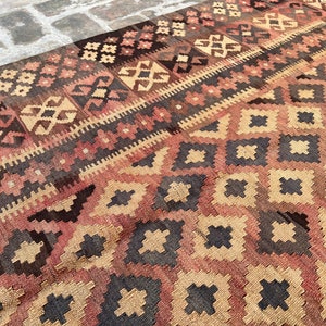 K&ouml;nnte beinhalten: Ein traditioneller t&uuml;rkischer Teppich mit einem geometrischen Muster in Braun-, Rot- und Beiget&ouml;nen. Der Teppich zeigt ein sich wiederholendes Rautenmuster mit filigranen Details.