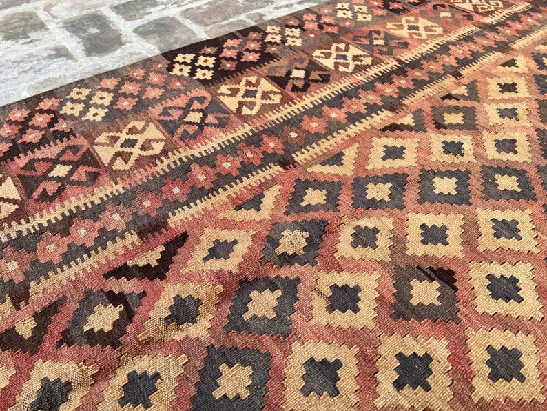 K&ouml;nnte beinhalten: Ein traditioneller t&uuml;rkischer Teppich mit einem geometrischen Muster in Braun-, Rot- und Beiget&ouml;nen. Der Teppich zeigt ein sich wiederholendes Rautenmuster mit filigranen Details.