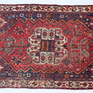 Pu&ograve; includere: Un tappeto vintage rosso, blu e crema con un motivo geometrico. Il tappeto ha un bordo con frange ed &egrave; in buone condizioni.