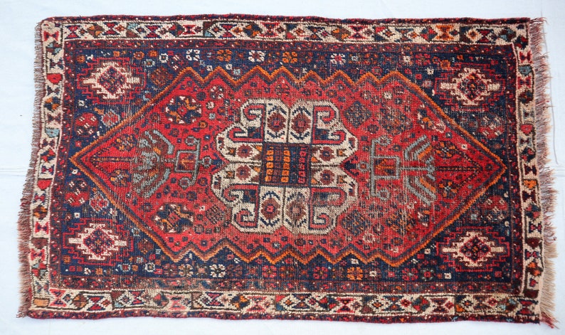Pu&ograve; includere: Un tappeto vintage rosso, blu e crema con un motivo geometrico. Il tappeto ha un bordo con frange ed &egrave; in buone condizioni.