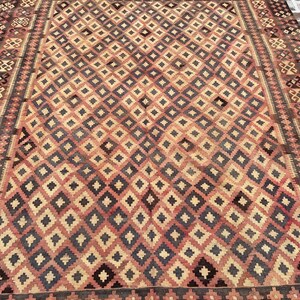 K&ouml;nnte beinhalten: Ein Vintage-Teppich mit einem geometrischen Muster in Rot-, Braun- und Cremet&ouml;nen. Der Teppich hat ein Rautenmuster mit einem Rand aus komplizierten Designs.