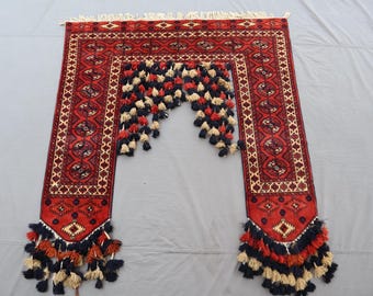 Op de afbeelding: Een rood en crèmekleurig tapijt met een centraal boogontwerp, met ingewikkelde patronen en decoratieve kwasten in marineblauw, crème en rood. Het tapijt heeft een rechthoekige vorm met een gedetailleerde rand.