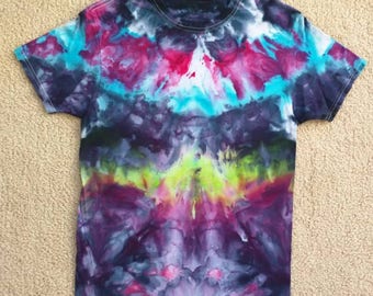 May include: A tie-dye t-shirt with a vibrant color scheme of blue, pink, purple, and green. The shirt has a symmetrical design with a dark center and lighter edges.