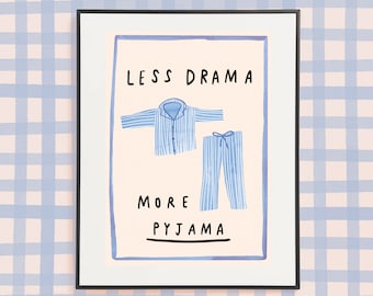 May include: A framed print with the text "Less Drama More Pyjama" in black lettering. The print features a blue and white striped pajama top and pants.