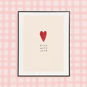 May include: A framed print with a red heart and the text "RICH WITH LOVE" on a light pink and white gingham background.