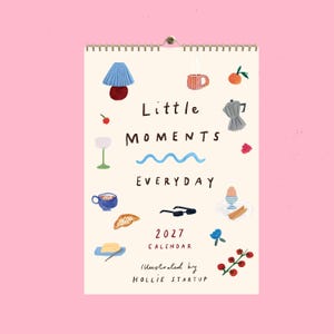 Puede incluir: Un calendario de pared para 2027 titulado Little Moments Everyday, ilustrado por Hollie Startup. La página de color crema presenta iconos dibujados a mano que incluyen una lámpara, una taza, fruta, cafetera, vaso, cruasán, gafas y un huevo.