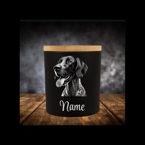 Könnte beinhalten: Schwarzweiß-Illustration eines Deutsch Kurzhaar-Hundes auf einem schwarzen Kerzengefäß mit Bambusdeckel. Das Gefäß trägt den Schriftzug "Name" auf der Vorderseite.