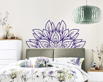 May include: A bedroom scene featuring a bed with floral bedding, a gray headboard, and a purple rug. A large purple mandala wall decal is above the bed. White dressers and a green chair complete the room's decor.