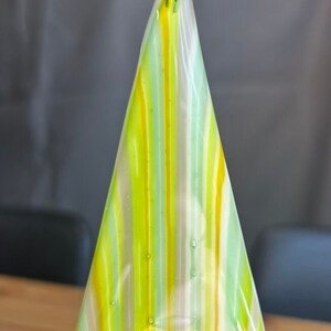 May include: A triangular glass ornament with a striped pattern in shades of green, yellow, and white.