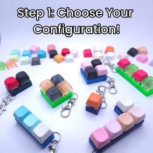Op de afbeelding: Een assortiment kleurrijke keycap-sleutelhangers. De keycaps zijn in verschillende kleuren, waaronder roze, blauw, oranje en zwart. De tekst "Step 1: Choose Your Configuration!" staat bovenaan de afbeelding.