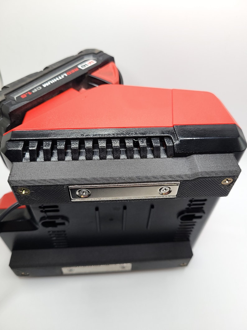 Peut inclure: Un outil &eacute;lectrique rouge et noir avec le texte "18V RED LITHIUM CP 1.5" sur le c&ocirc;t&eacute;. L'outil a une base noire avec une plaque m&eacute;tallique et deux vis.