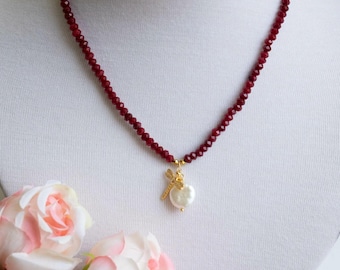 May include: A red beaded necklace with a gold pendant featuring a pearl and a dragonfly design.