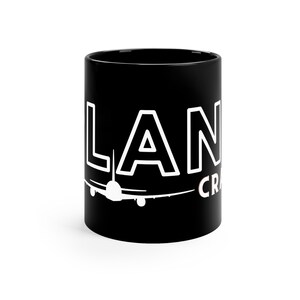 May include: Black ceramic mug with white text that reads "LANDING CRAFT" and a white silhouette of an airplane.