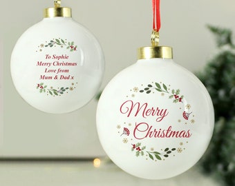 May include: Two white spherical Christmas ornaments with gold caps and red ribbons. One features a red Merry Christmas script inside a botanical wreath. The other displays the text To Sophie Merry Christmas Love from Mum & Dad x inside a wreath.