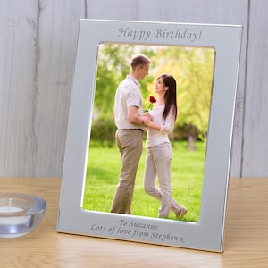 May include: Silver photo frame with a personalised inscription that reads "Happy Birthday! To Suzanne Lots of love from Stephen X". The frame holds a photo of a couple standing in a grassy field.