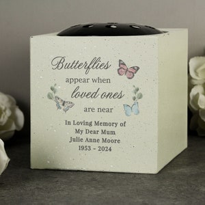May include: A light green speckled cube-shaped memorial vase with a black flower frog lid. The front features the text "Butterflies appear when loved ones are near" and "In Loving Memory of My Dear Mum Julie Anne Moore 1953 - 2024" with butterfly illustrations.