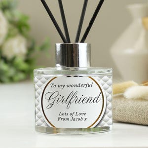 May include: A clear glass diffuser bottle with a silver lid and black reeds. The bottle has a white label with a gold border and the text "To my wonderful Girlfriend Lots of Love From Jacob x".