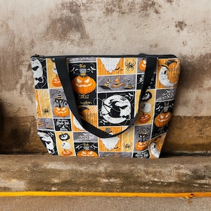 May include: Black and orange Halloween-themed tote bag with a patchwork design featuring pumpkins, bats, witches, and the text "The Great Pumpkin", "October 31st", and "Old Salem's Black Cat Racing".