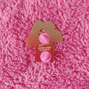 May include: Gold-colored metal pin shaped like a tree with the text "FOR COLD MISLUCK" and the words "by ColorKute" underneath. The pin has two pink plastic butterfly backings.