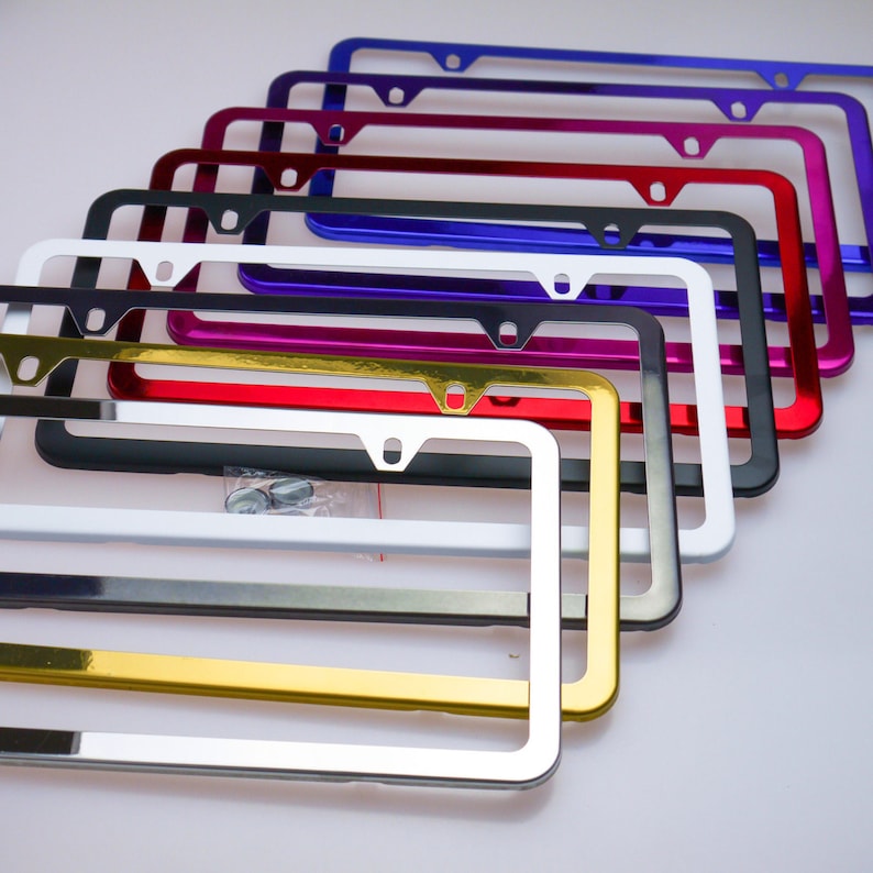 May include: A set of ten license plate frames in various colors, including gold, silver, red, purple, blue, black, and white. The frames are made of metal and have a shiny finish.