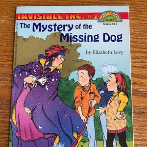 May include: A book cover for "Invisible Inc. #2: The Mystery of the Missing Dog" by Elizabeth Levy. The cover features a cartoon illustration of a woman in a purple and pink robe with stars and a crescent moon, a boy in an orange shirt, a girl in a yellow shirt, and a white dog.