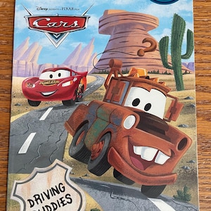 May include: A book cover featuring the characters Mater and Lightning McQueen from the Disney Pixar movie Cars. The cover is red, orange, and blue with the title "Step into Reading" and "Driving Buddies".